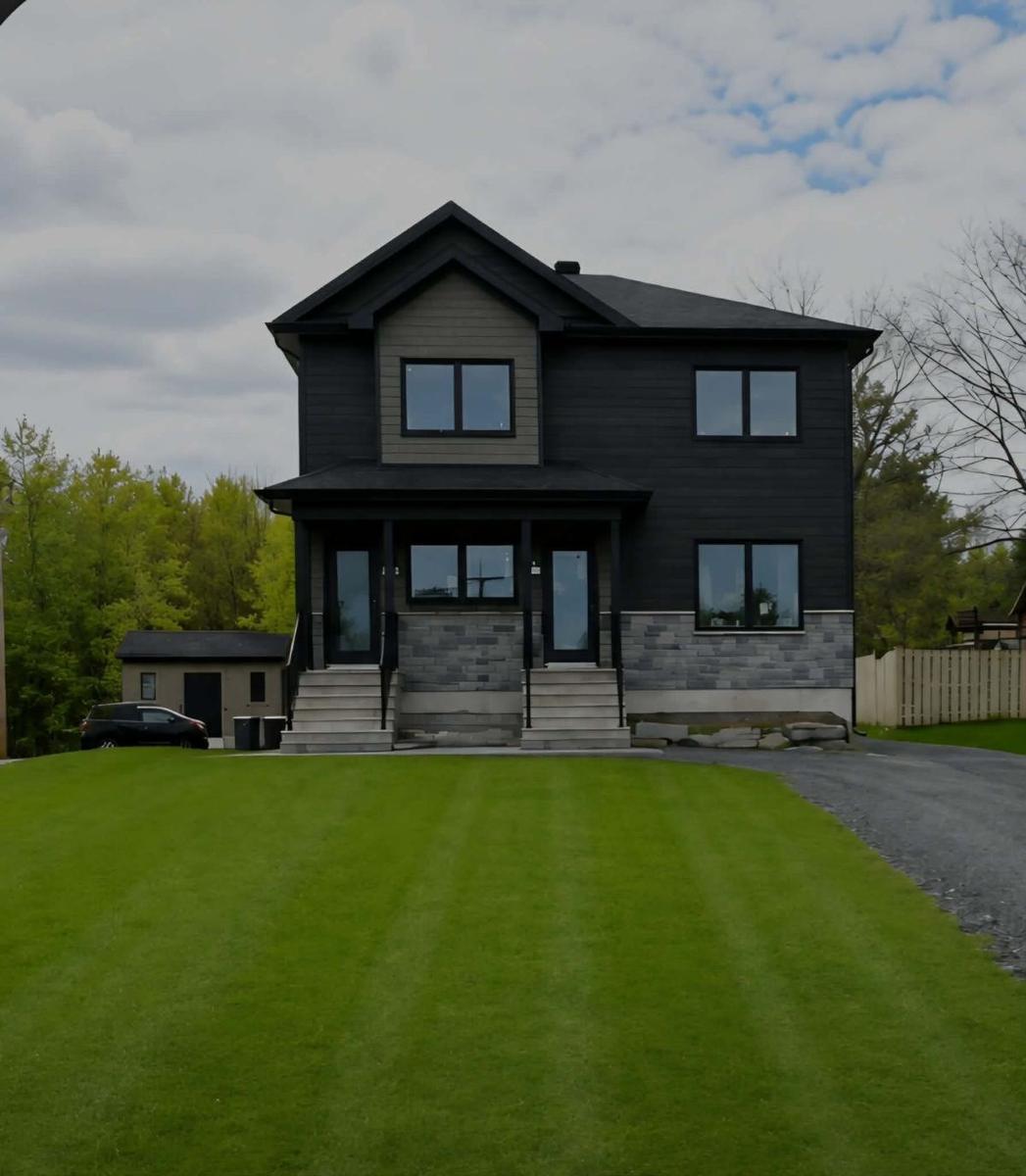 Maison moderne à façade grise et toit noir construite par Immo GB